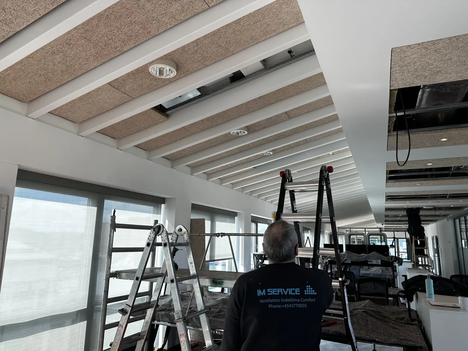 Technician surveying a ceiling ventilation installation