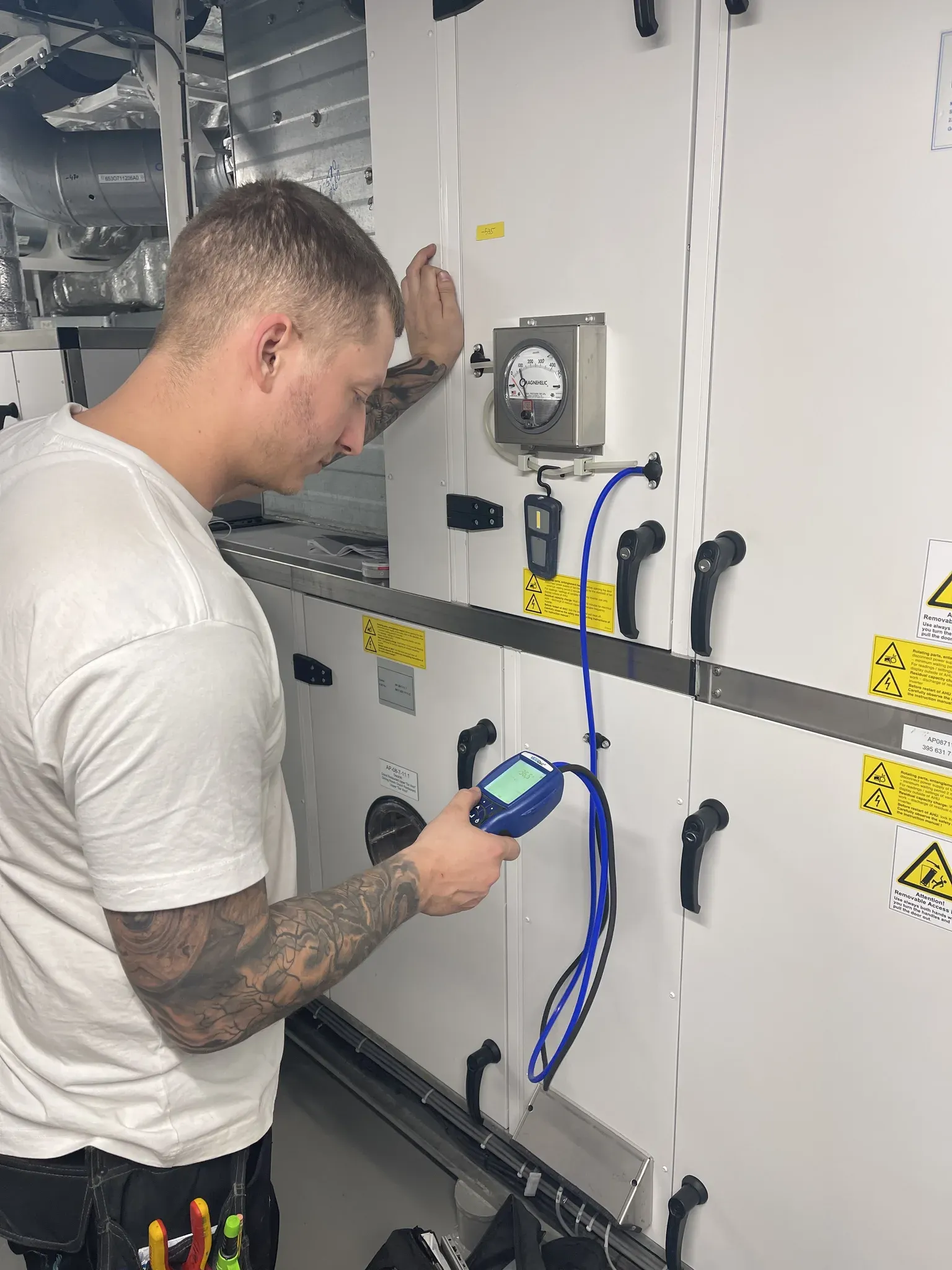 Technician measuring and commissioning HVAC equipment with calibrated instruments